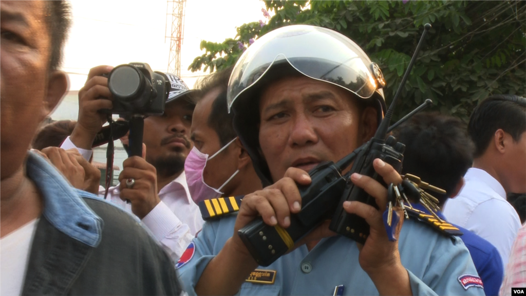 A traffic police officer talks on his walkie-talkie to facilitate the traffic for the demonstrators during the protest against CNRP's acting president, Kem Sokha. (Pin Sisovann/VOA Khmer)