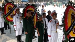 Former Vietnam Communist General Secretary Le Kha Phieu, center, stands between wreaths before paying respects to the late Gen. Vo Nguyen Giap at the National Funeral House in Hanoi, Vietnam, Oct. 12, 2013. 