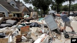 Volunteer Paul Hancock pushes an oven damaged by floodwaters onto a pile of debris in the aftermath of Hurricane Harvey on Sunday, Sept. 3, 2017, in Spring, Texas. Hancock and numerous other volunteers are helping flood victims across the Houston area.