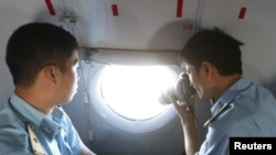 在越南土珠岛附近参加搜救的越南空军人员在飞机上对海面进行拍照。（2014年3月10日）