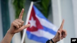 Los manifestantes realizan la letra "L", por la libertad y ondean banderas, el 14 de julio de 2021, en el barrio de La Pequeña Habana de Miami, Estados Unidos.