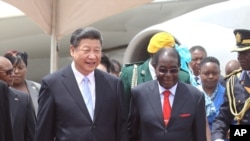 Chinese President Xi Jinping, right, and Zimbabwean President Robert Mugabe hold hands upon his arrival in Harare, Zimbabwe, Tuesday, Dec. 1. 2015.