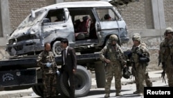 Afghan and foreign security forces keep watch at the site of car bomb attack in Kabul, May 17, 2015. 