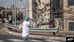 Un agent de santé sud-africain porte un équipement de protection individuelle (EPI) complet alors qu'elle se promène à l'intérieur de l'hôpital Chris Hani Baragwanath à Soweto, le 18 juillet 2020.
