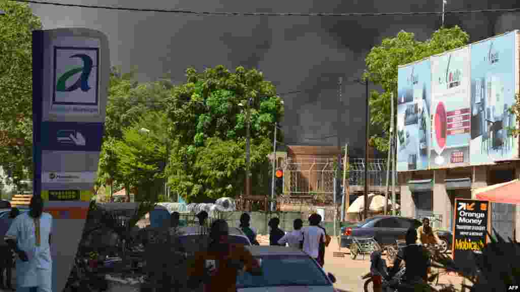 Plusieurs témoins regardent une épaisse colonne de fumée noire au niveau de l'état-major des armées à Ouagadougou, Burkina Faso, le 2 mars 2018.