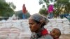 Seorang ibu menggendong bayinya saat antre makanan di sekolah dasar Tsehaye, yang diubah menjadi tempat penampungan sementara bagi orang-orang yang terlantar akibat konflik, di kota Shire, wilayah Tigray, Ethiopia, 15 Maret 2021. (REUTERS/Baz Ratner)