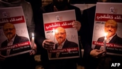 Manifestantes portan carteles y velas para protestar por el asesinato del periodista saudí Jamal Khashoggi fuera del consulado del reino en Estambul. Foto del 25 de octubre de 2018.