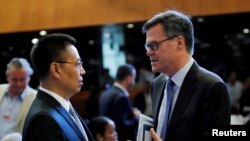 美國駐WTO大使習達難(右)在瑞士日內瓦舉行的世界貿易組織（WTO）會議上與中國駐WTO大使張向晨交談。（2018年7月26日）