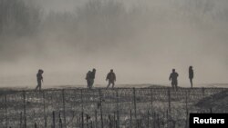 ARCHIVO: Un grupo de migrantes es detenido por miembros de la Guardia Nacional de Estados Unidos en Eagle Pass, Texas, visto desde Piedras Negras, México, el 4 de febrero de 2024.