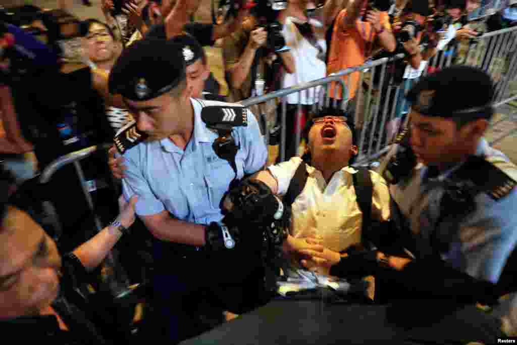 Student protest leader Joshua Wong shouts as he is carried away by policemen while protesters are arrested at a monument symbolizing the city's handover from British rule to Chinese rule, a day before Chinese President Xi Jinping is due to arrive for the celebrations, in Hong Kong.
