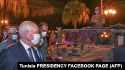 A picture provided by the Tunisian presidency Facebook page on July 26, 2021, shows Tunisian President Kais Saied walking past a military vehicle in Tunis's central Habib Bourguiba Avenue.