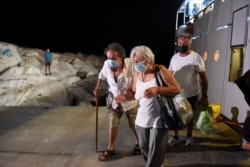 People are evacuated on a ferry as a wildfire burns in the village of Psaropouli, on Evia island, Greece, Aug. 8, 2021.