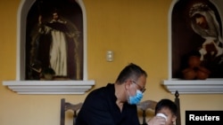 Fray Carlos Cáceres le da una bebida a un niño no acompañado que fue deportado de Estados Unidos, y ahora está en un refugio en la Ciudad de Guatemala. 31 de julio de 2020.
