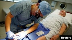 Archivo - El doctor Andy Chiou atiende una herida en la pierna del paciente Larry Kirk en Peoria, Illinois, 26 de noviembre de 2013.