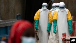 FILE— In this July 16, 2019 photo, health workers dressed in protective gear begin their shift at an Ebola treatment center in Beni, Congo DRC. 