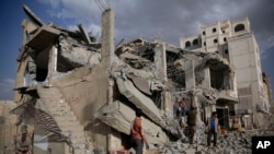 FILE - Yemeni men inspect a house destroyed by a Saudi-led airstrike in Sanaa, Yemen, Monday, Jan. 25, 2016. 