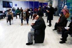 FILE - People wait at the reception hall of a COVID-19 vaccination mega center in Athens, Feb. 15, 2021.