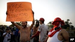 Seorang pengunjuk rasa menunjukkan poster bertuliskan dalam bahasa Spanyol: "Pahlawan. Kami menunggumu. Kebebasan. Ayo Venezuela" di La Parada, Kolombia, 25 Februari 2019, di perbatasan dengan Venezuela. 