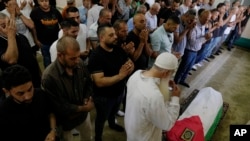 Dolientes palestinos rezan junto al cuerpo de Mohammad Hoshiya, de 12 años, durante su funeral en la aldea cisjordana de Qatana, al suroeste de Ramala, el 22 de junio de 2024.