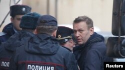 Le leader de l’opposition russe Alexei Navalny est flanqué par des policiers lors de son arrivée au tribunal de Tverskoi, à Moscou, Russie, 27 mars 2017.
