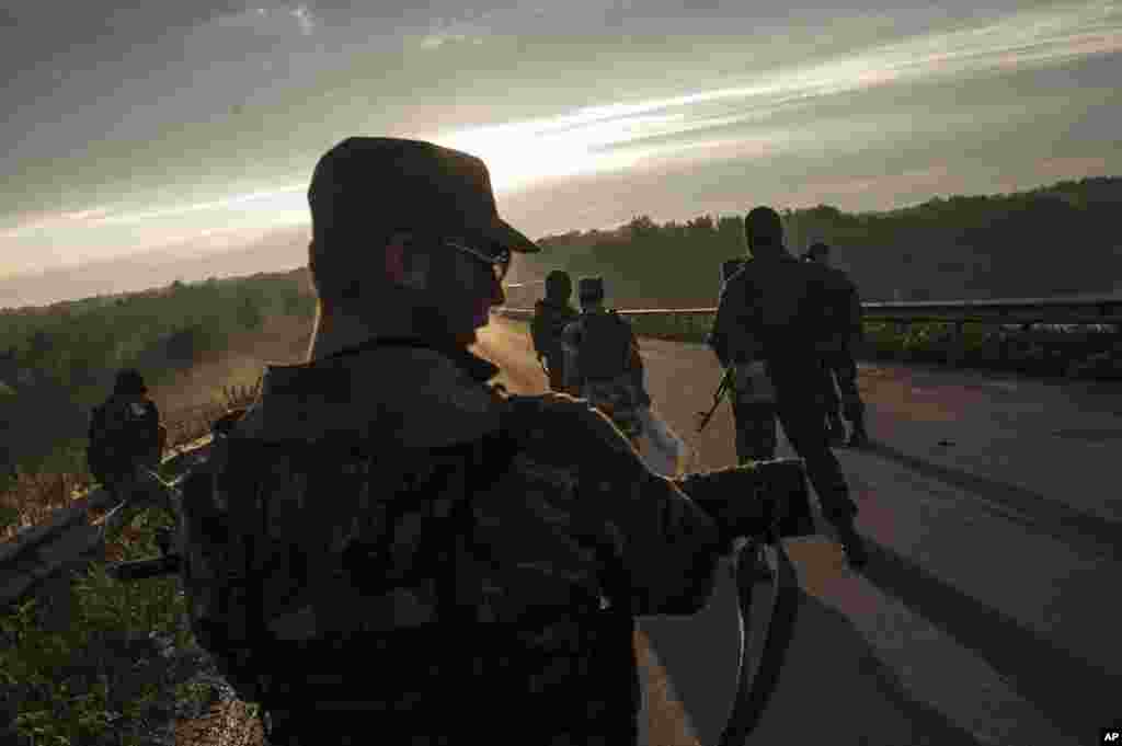 Pro-Russian fighters wait for representatives of the Ukrainian troops at a checkpoint in the village of Karlivka for the handover of the bodies of Ukrainian troops who died in a plane shot down near Luhansk, Ukraine, June 18, 2014.