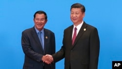 Cambodian Prime Minister Hun Sen, left, and Chinese President Xi Jinping, right, shake hands during the welcome ceremony for the Belt and Road Forum, at the International Conference Center at Yanqi Lake in Beijing, Monday, May 15, 2017. (Roman Pilipey/Pool Photo via AP)