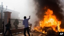 Un véhicule brûle devant le siège du parlement lors des manifestations de rue à Ouagadougou, Burkina Faso, 30 octobre 2014.