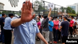 六月初，新冠病毒在北京死灰复燃，让人们再度如临大敌。图为北京市民在一体育中心排队进行新冠病毒核酸检测，一名警察做出禁止的手式。（路透社2020年6月17日资料照）