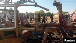 FILE - People walk past a destroyed vehicle following shelling by the Rapid Support Forces, in Omdurman, Sudan, Dec. 10, 2024. (Khartoum state government via Reuters)