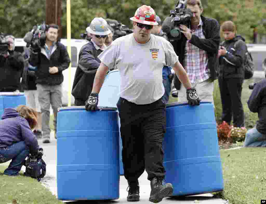 Workers move disposal barrels to a staging area outside the apartment of a health care worker who treated Ebola patient Thomas Eric Duncan and tested positive for the disease, in Dallas, Oct. 13, 2014.