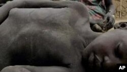 A four-year-old Sudanese boy lies on the ground after collapsing from hunger at a feeding centre in Rumbek, May 25, 2005. Thirteen people have died of hunger after crops failed in Eastern Equatoria state.
