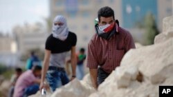 Palestinian demonstrators take cover during clashes with Israeli troops near Ramallah, West Bank, Sept. 29, 2015.