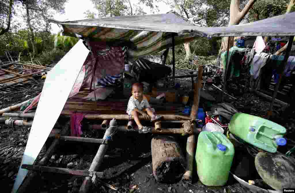 A child sits amid the remains of a house destroyed by Typhoon Rammasun in Batangas city, south of Manila, July 17, 2014.