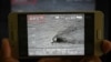 A Pakistani journalist watches a video released by Pakistan's Navy that allegedly shows an Indian submarine, on a smartphone in Islamabad on March 5, 2019.