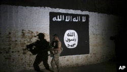 FILE - An Iraqi soldier inspects a tunnel adorned with an Islamic State group flag, March 1, 2017.
