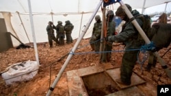 Israeli soldiers stand around the opening of a hole that leads to a tunnel that the army says crosses from Lebanon to Israel, near Metula, Dec. 19, 2018.