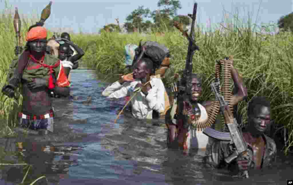 Des rebelles patrouillent et protègent des civiles de l’ethnie Nuer qui marchent à travers des zones noueuses enfin d’aller au marché de des déplacés situés près de la Mission Onusienne au Sud Soudan (UNMISS) au village de Bentiu, au Sud Soudan.