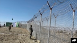 FILE - Pakistani soldiers stand guard at a fence between Pakistan and Afghanistan at Angore Adda, Pakistan, Oct. 18, 2017.