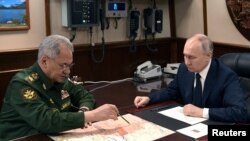 Президент Росії Володимир Путін слухає міністра оборони Сергія Шойгу під час наради після церемонії підняття прапора на фрегаті "Адмірал Головко", прийнятого до складу ВМФ Росії на корабельні в Санкт-Петербурзі, 25 грудня 2023 року. (Фото: Sputnik/Олексій Данічев)