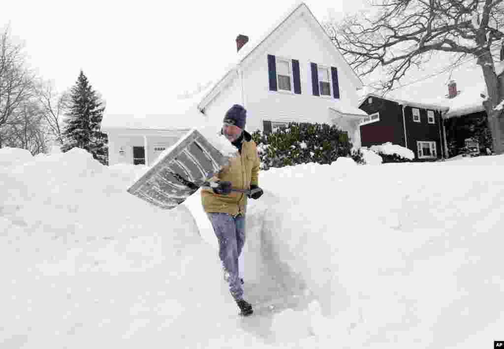 Tom Mulkern, de Norwood, Mass., enlève de la neige avec une pelle devant sa maison le dimanche 15 février 2015, à Norwood.