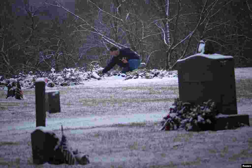 A man touches the snow covered grave of six-year-old Ana Grace Marquez-Greene, one of 20 schoolchildren killed in the December 14 shootings at Sandy Hook Elementary School, at the Newtown Village Cemetery, Connecticut, December 25, 2012.