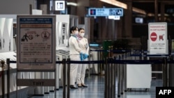 Anggota staf penerbangan berdiri di gerbang keberangkatan Bandara Internasional Haneda Tokyo pada 29 November 2021, ketika Jepang mengumumkan rencana untuk melarang semua pelancong asing baru atas varian omicron dari COVID-19. (Foto: AFP)