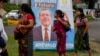 Varias personas pasan frente a un cartel electoral del candidato Bernardo Arévalo, quien encabeza las encuestas para la segunda vuelta de elecciones presidenciales en Guatemala, el 15 de agosto de 2023.