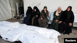 Para pelayat duduk di samping jenazah warga Palestina yang terbunuh dalam serangan oleh Israel, di tengah perang antara Israel dan kelompok Hamas Palestina, di Rumah Sakit Abu Yousef al-Najjar di Rafah, bagian selatan Jalur Gaza, Jumat, 3 Mei 2024. (Foto: Hatem Khaled/Reuters)
