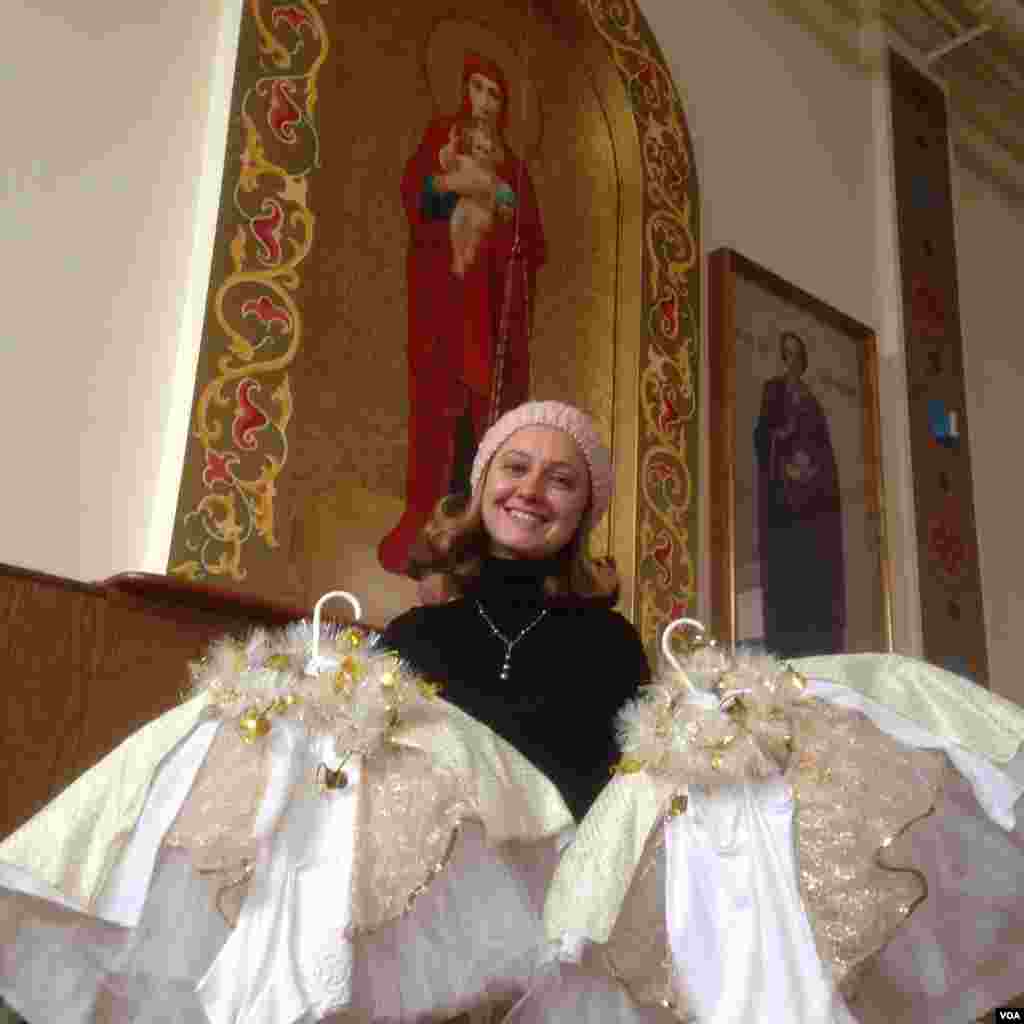 Choir Director Zlata Mishima, a recent Russian immigrant, holds the costumes for the Snow Queen portion of the Christmas Pageant. (Adam Phillips/VOA)