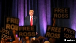 La gente sostiene carteles en apoyo del encarcelado fundador del mercado de la red oscura Silk Road, Ross Ulbricht, mientras el expresidente de EEUU, Donald Trump, asiste a la convención nacional del Partido Libertario en Washington, el 25 de mayo de 2024.