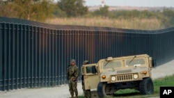 ARCHIVO - Miembros de la Guardia Nacional vigilan una valla cerca del puente internacional donde acampan miles de migrantes haitianos, en septiembre de 2021.