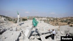 Bendera Hamas berkibar di atas puing-puing rumah Hussam Kawasme, salah seorang warga Palestina yang dicurigai menculik dan membunuh tiga remaja Israel pada Juni di kota Hebron, Tepi Barat (18/8).