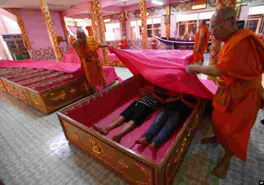 Los monjes cubren a los fieles que descansan en ataúdes en el templo de Takien en los suburbios de Bangkok, Tailandia, el lunes 31 de diciembre de 2018. Los fieles creen que la ceremonia del ataúd, que simboliza la muerte y el renacimiento, los ayuda a librarse de la mala suerte y nacen de nuevo para un nuevo comienzo en el año Nuevo.