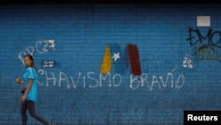 Una mujer pasa frente a un graffiti de la campaña de Nicolás Maduro para las elecciones presidenciales en Venezuela el 8 de mayo de 2018. Foto: Reuters/Adriana Loureiro.